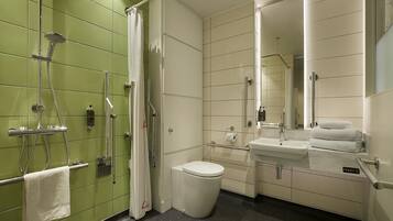 A bathroom with a shower, toilet, sink, and a mirror.