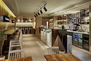 A bar area with seating, a counter with a menu, and a refrigerated display. - Hub By Premier Inn London Covent Garden (London)