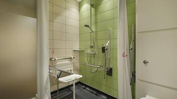 A bathroom with a shower, grab bars, and a toilet.