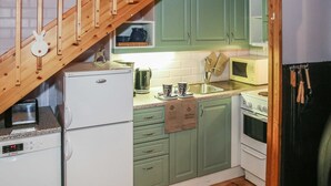 A compact kitchen with a wooden staircase, a Bosch refrigerator, a microwave, and a stove. - Yllästokka 7 by Interhome (Ylläsjärvi)