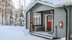 A wooden cabin with a red door, a fire extinguisher, and skis leaning against the wall. - Yllästokka 7 by Interhome (Ylläsjärvi)