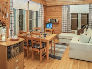 A cozy cabin interior with a dining area, a television, and a sofa.