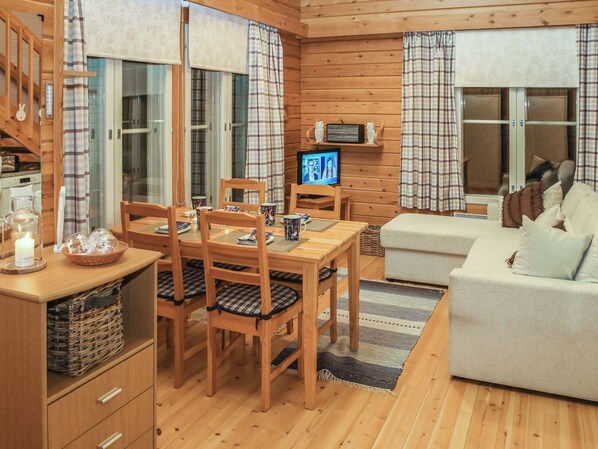 A cozy cabin interior with a dining area, a television, and a sofa.