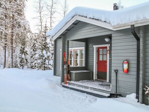 A small, single-story building with a red door and a covered porch.