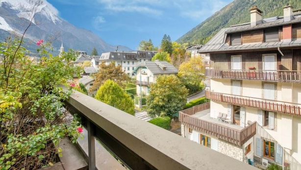 A mountain village with traditional buildings, a balcony, and a view of the mountains.