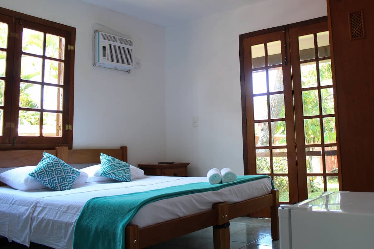 Ein Schlafzimmer mit Bett, Nachttisch, Fenster und Kleiderschrank.