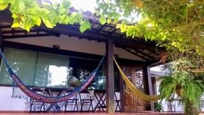 Un espacio de estar al aire libre cubierto con una hamaca, sillas y plantas en macetas.