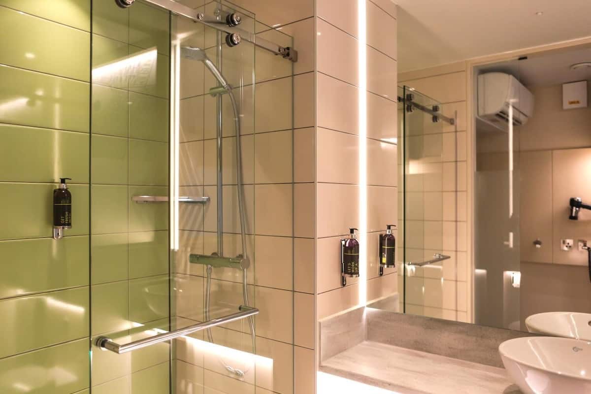Un baño moderno con cabina de ducha de vidrio, tocador con espejo y lavabo.