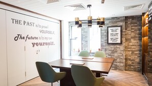 Un salón de conferencias con una cita grande en la pared, una mesa de madera y dos sillas.