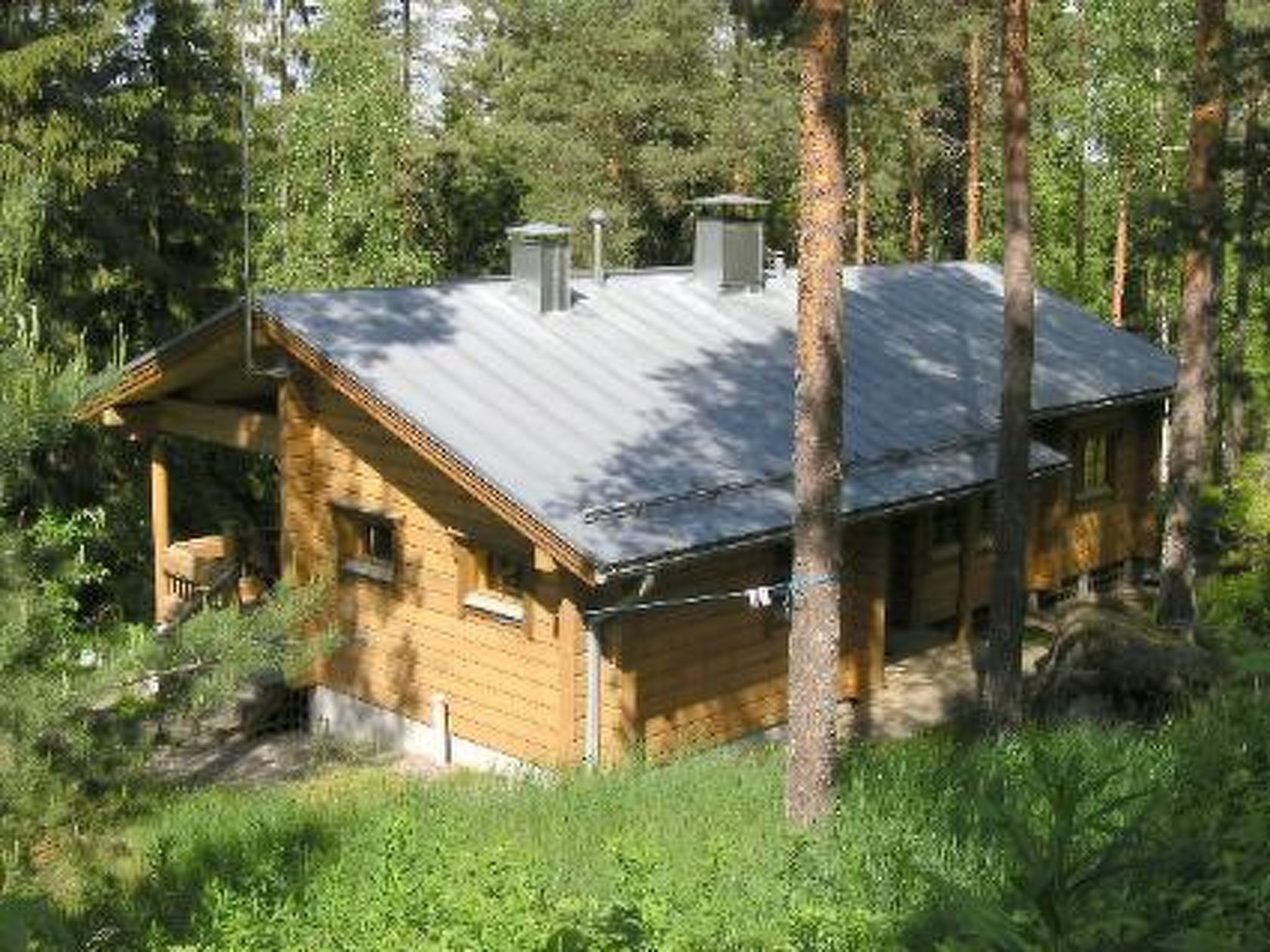 Eine Holzhütte mit einem Metall-Dach, umgeben von Bäumen.