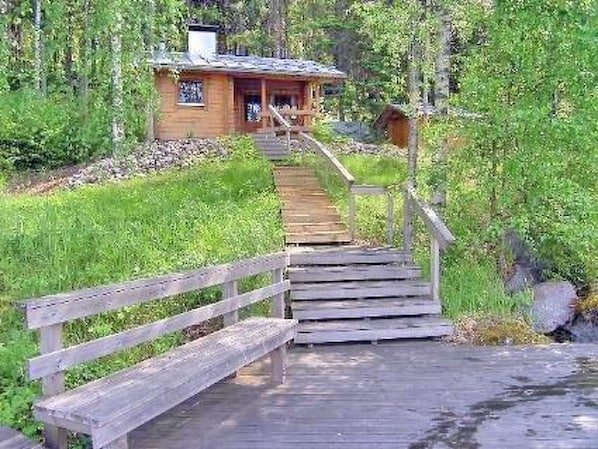 A wooden staircase leading to a cabin surrounded by greenery.