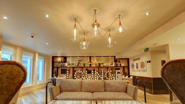 A lounge area with a sofa, a table, and a chandelier. - hub by Premier Inn London Tottenham Court Road (Goodge Street) (London)