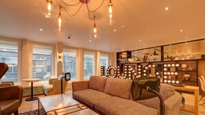 A modern living room with a sofa, a coffee table, and a chandelier. - hub by Premier Inn London Tottenham Court Road (Goodge Street) (London)