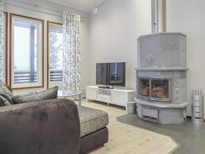 Una sala de estar moderna con un sofá gris, un televisor de pantalla plana, una chimenea y un balcón con vistas.