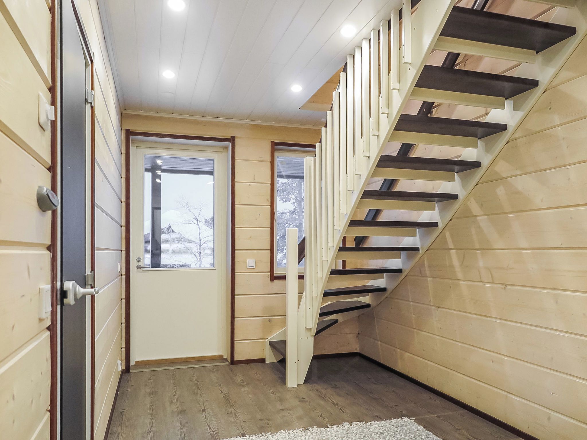 A wooden interior with a staircase, a door, and a window.