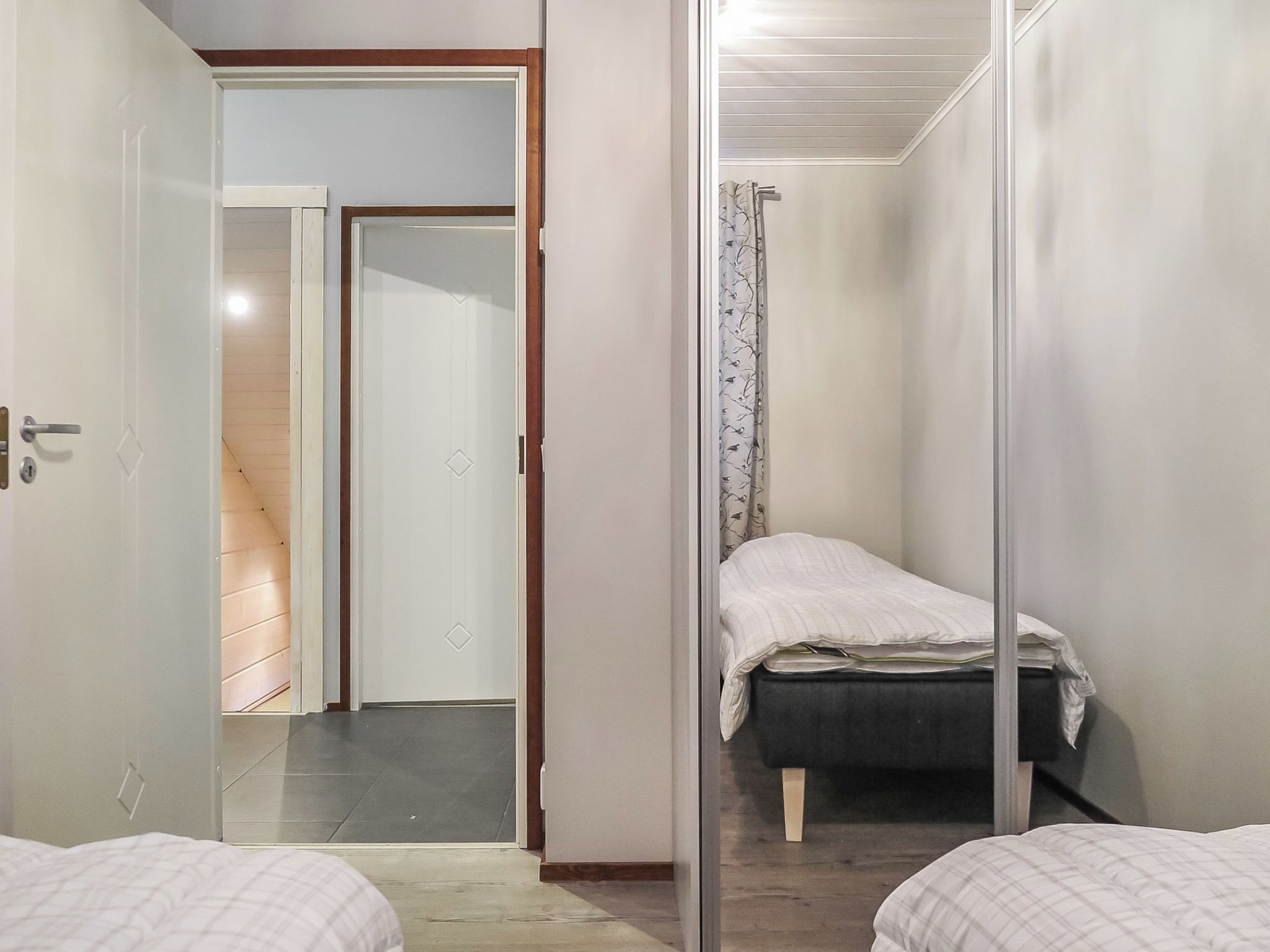 Una habitación pequeña con cama, puerta y espejo.