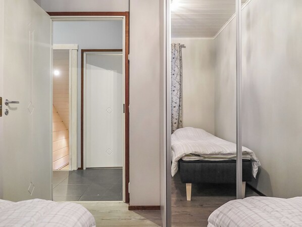Una habitación pequeña con cama, puerta y espejo.