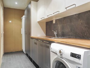 Een kleine keuken met een ingebouwde wasmachine, een spoelbak en een koelkast.