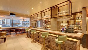 Eine Bar mit Barhocker, Theke und Weinkühlschrank.