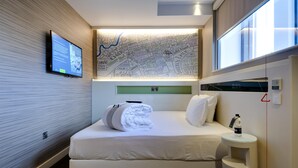 A hotel room with a bed, a flat-screen TV, a wall map, a small table with a bottle, and a window. - Hub By Premier Inn London City Bank (London)