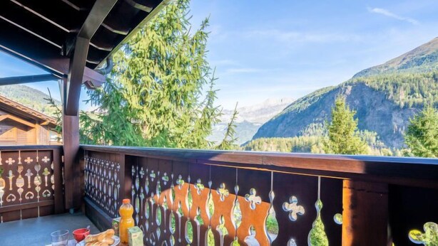 A balcony with a wooden table set for breakfast, overlooking a mountainous landscape. - Les Hauts des Chavants - by Interhome (Les Houches)