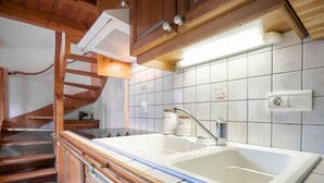 A kitchen with a double sink, wooden cabinets, a stainless steel faucet, and a tiled backsplash. - Les Hauts des Chavants - by Interhome (Les Houches)