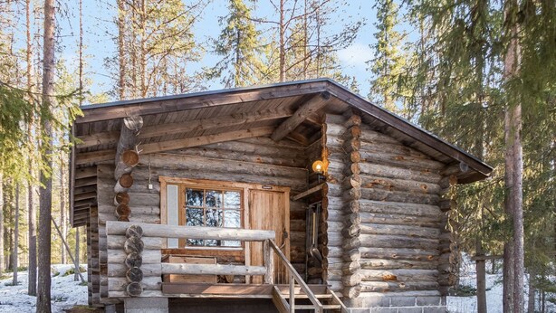 A log cabin with a wooden staircase leading to a window, surrounded by snow and trees. - Retkietappi honkapirtti by Interhome (Kuusamo)