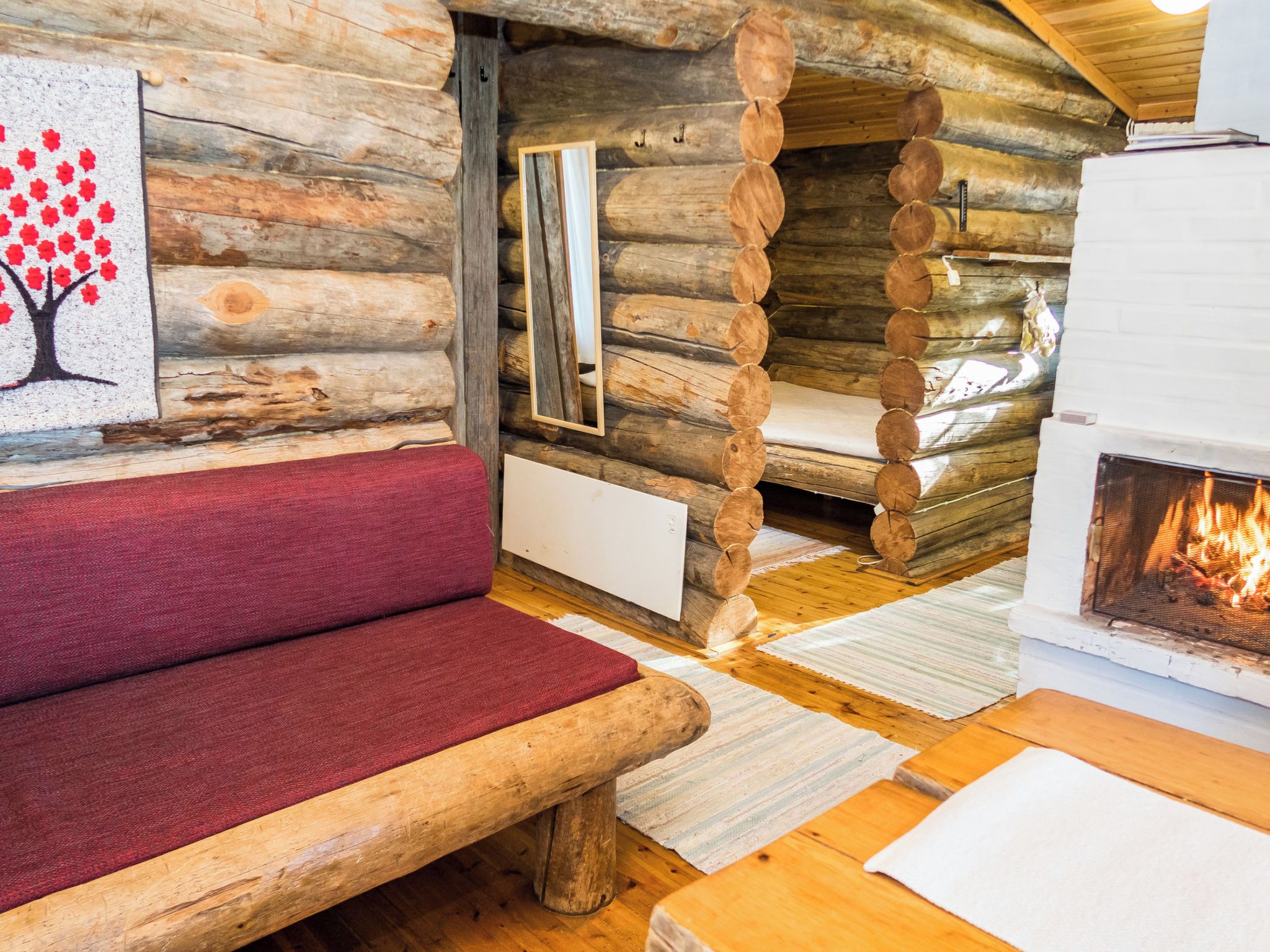 Ein Blockhaus-Interieur mit einer hölzernen Bank, einem Kamin und einem Spiegel an der Wand.