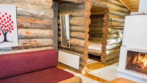 A log cabin interior with a red sofa, a fireplace, and a mirror on the wall. - Retkietappi honkapirtti by Interhome (Kuusamo)