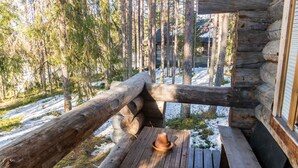 A rustic cabin with a wooden deck and a table with a hat. - Retkietappi honkapirtti by Interhome (Kuusamo)