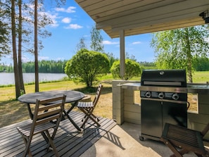 An outdoor patio with a grill, a table, and chairs.