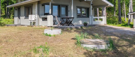 A cabin with a covered porch, a fireplace, and a table and chairs outside.