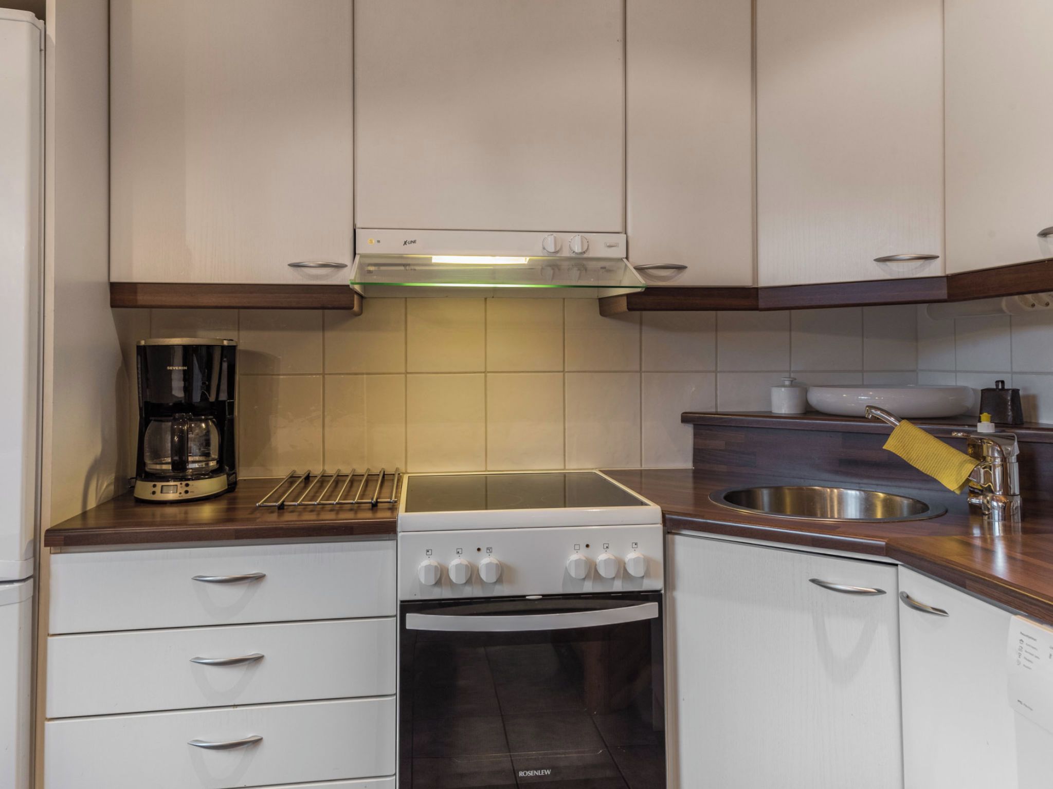 Une cuisine compacte équipée d’une cuisinière, d’un four et d’une machine à café posée sur le plan de travail.