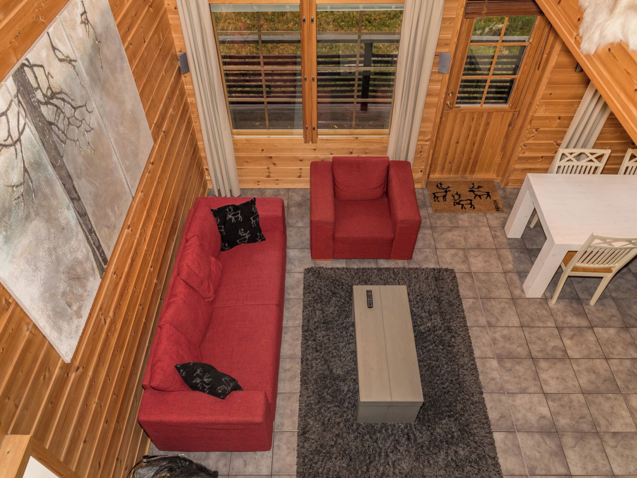 L’intérieur d’un chalet accueillant, avec un canapé rouge, un fauteuil assorti, une petite table et un ensemble de salle à manger.