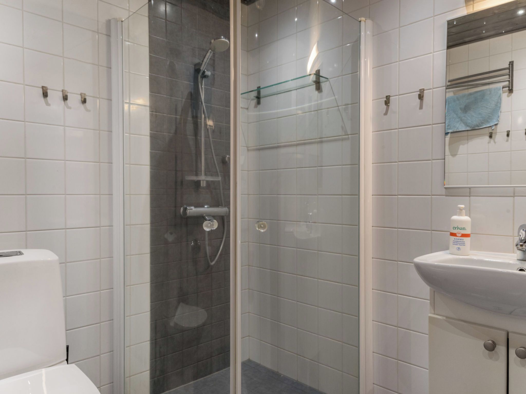 A modern bathroom with a glass-enclosed shower, a white sink, and a mirror with a towel.