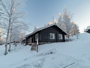 A cabin with a wooden exterior, a front porch, and a staircase leading up to the entrance. - Lomaylläs maja, palovaarankaarre 6 a by Interhome (Ylläsjärvi)