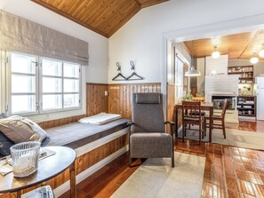 Una sala de estar acogedora con un banco empotrado, un comedor con muebles de madera y una cocina con pared de ladrillo y luces colgantes.
