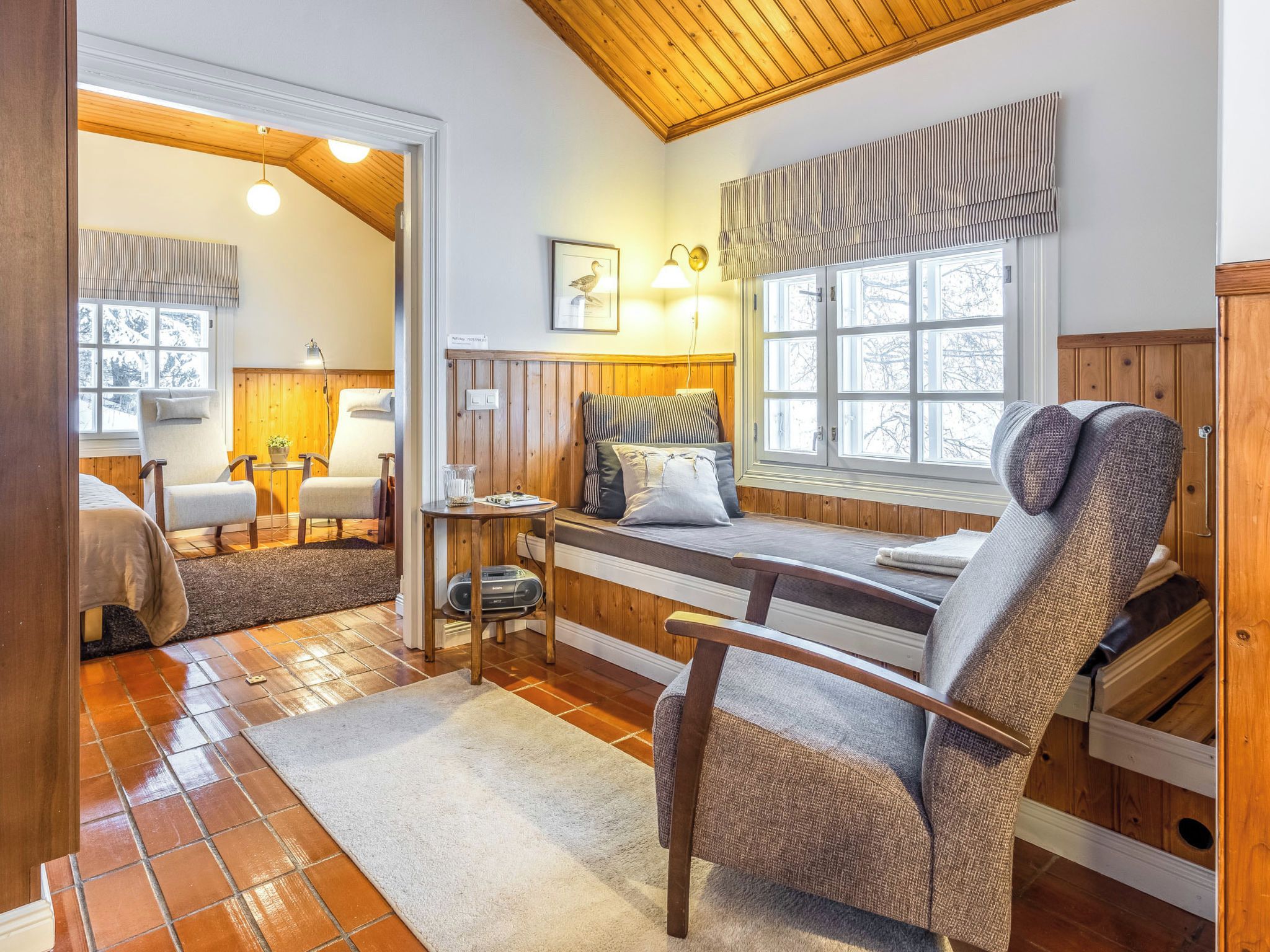Een gezellige kamer met een bed, een stoel, een tafel en een raam met uitzicht.