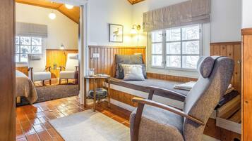 Een gezellige kamer met een bed, een stoel, een tafel en een raam met uitzicht.
