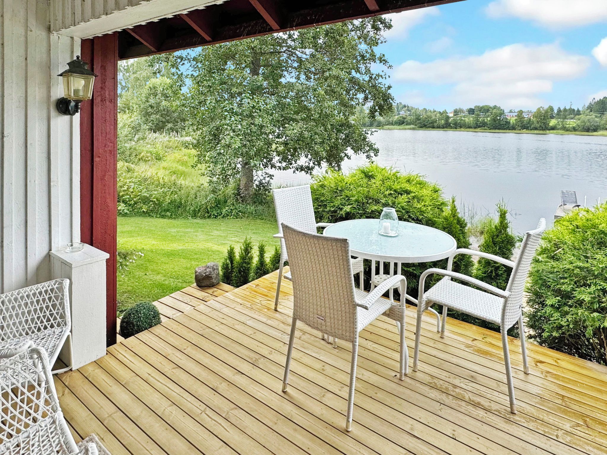 A wooden deck with a table and chairs overlooking a lake.