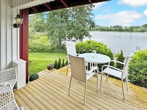 Eine Holzterrasse mit Tisch und Stühlen mit Blick auf einen See.