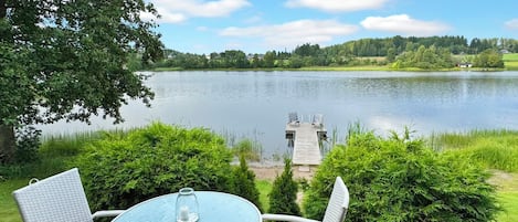 A deck with wicker furniture and a view of a lake.