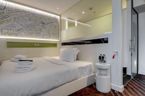 Relax in a spacious room with a large bed, bedside table, and glass shower enclosure.