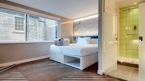 Una habitación de hotel moderna con una cama, un mapa en la pared, una ventana y una zona de ducha.
