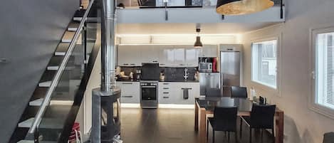 Una cocina moderna con comedor, una escalera y vistas al exterior.