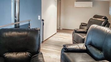 Une pièce avec deux canapés en cuir, un plancher en bois et un mur blanc avec une fenêtre.