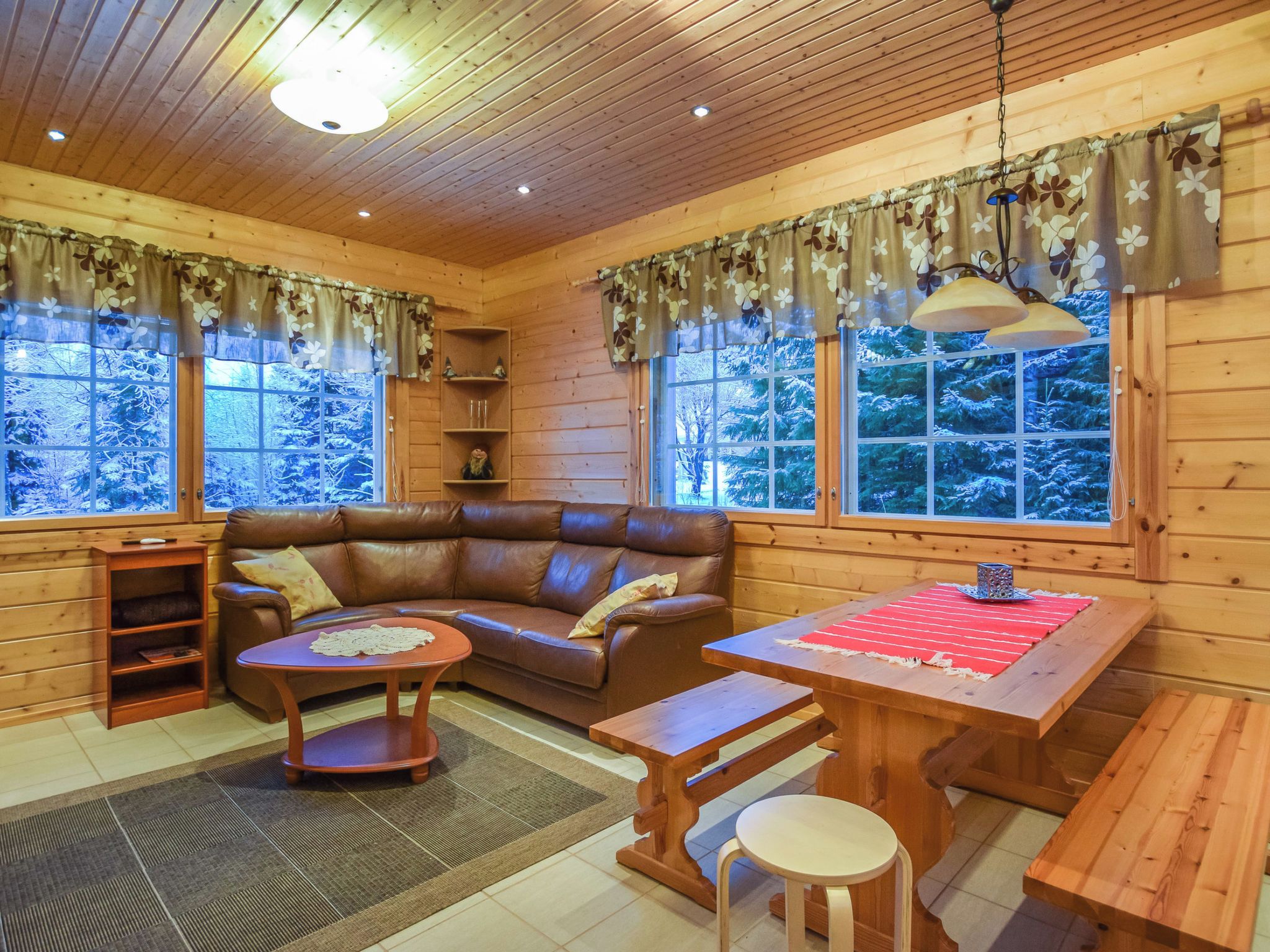 Een gezellig interieur van een chalet met een leren bank, een houten eettafel en een open haard.
