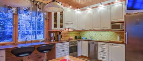 Een moderne keuken met witte kasten, roestvrijstalen apparatuur en een houten plafond.