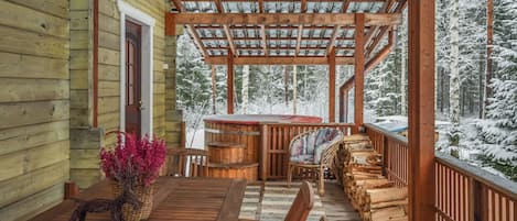 Un patio in legno con zona relax coperta, un tavolo e una pianta in vaso.