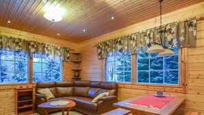 Interior acolhedor de uma cabana com um sofá de couro, uma mesa de madeira e um banco.